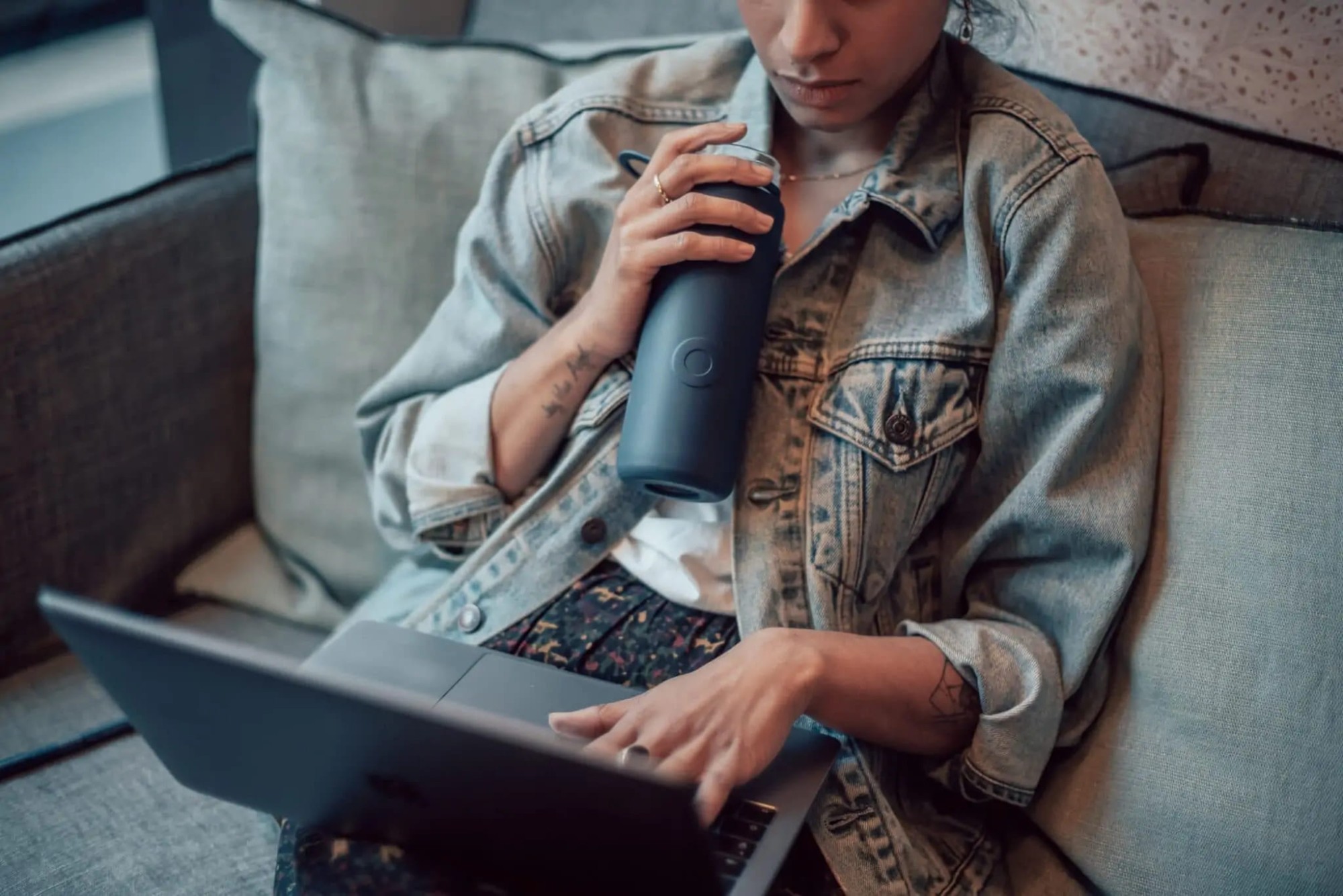 kobieta trzymająca bidon pracując na laptopie